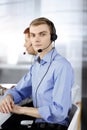 Two young men in headset, sitting at the desk in a sunny modern office, listening to the clients. Call center operators Royalty Free Stock Photo