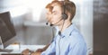 Two young men in headset, sitting at the desk in a sunny modern office, listening to the clients. Call center operators Royalty Free Stock Photo