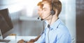 Two young men in headset, sitting at the desk in a sunny modern office, listening to the clients. Call center operators Royalty Free Stock Photo