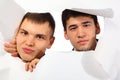 Two young men looking out in hole in paper Royalty Free Stock Photo