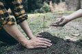 Two young men plowed the soil to plant trees, ready to grow into a large tree in the future, Plants help increase oxygen in the ai