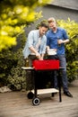 Two young men preparing barbecue in the courtyard Royalty Free Stock Photo