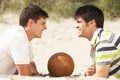 Two Young Men Relaxing On Beach With Football Royalty Free Stock Photo