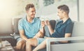 Two young men sitting on the sofa, talking and drinking wine after dinner together. Gay couple dating at home or in a restaurant Royalty Free Stock Photo