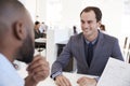 Two young men talking at a meeting in an open plan office Royalty Free Stock Photo