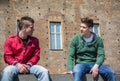 Two young men talking while sitting on curb Royalty Free Stock Photo