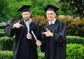 two young men-university graduates in robes and square hats are happy to receive a diploma. Royalty Free Stock Photo