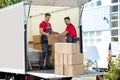 Young Men Stacking The Cardboard Boxes In Moving Truck