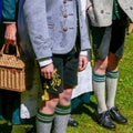 Two Young Men and a Woman wearing German traditional Bavarian clothing, standing in a sunny day. No faces