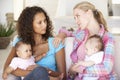 Two Young Mothers On Sofa At Home