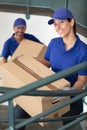 two young movers in blue uniform carrying cardboard boxes Royalty Free Stock Photo