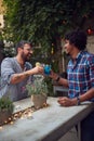 Two young multiethnic male laughing and toast with cocktails in outdoor cafe. multiethnic, friendship, socializing, leisure,