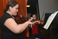 Two young women playing violins at a party