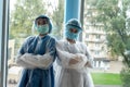 Two young nurses posing in the corridor of a modern clinic in protective clothing Royalty Free Stock Photo