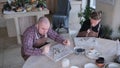 two young people with autism syndrome and with special physiological development are engaged in clay modeling sitting at