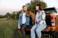 Two young people and a bully dog sitting on the cargo bed door of a pickup truck looking for peaceful time in the countryside