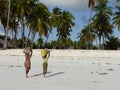 Two young people carrying sack of seaweed on beach, Jambiani, Zanzibar