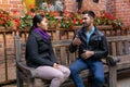 Young man and woman talking gesturing while sitting on a bench outdoors Royalty Free Stock Photo