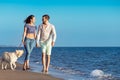 Two young people running on the beach kissing and holding tight with dog Royalty Free Stock Photo