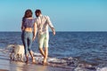 Two young people running on the beach kissing and holding tight with dog Royalty Free Stock Photo