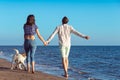 Two young people running on the beach kissing and holding tight with dog Royalty Free Stock Photo