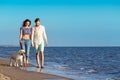 Two young people running on the beach kissing and holding tight with dog Royalty Free Stock Photo