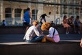 Two young people sitting in the sun on square in Barcelona chatting