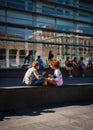 Two young people sitting in the sun on square in Barcelona chatting