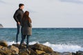 Two young people standing on a stone beach discussing the current situation