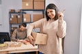 Two young people working at small business ecommerce smiling happy pointing with hand and finger to the side Royalty Free Stock Photo