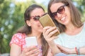 Two young persons looking at smartphone sharing and enjoying social media concept of lifestyle sharing having fun outdoors