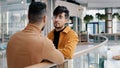 Two young positive indian guys standing in lobby talking discussing business problem carefree friends discussing sharing Royalty Free Stock Photo