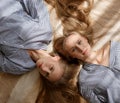 Two young pretty caucasian twin sisters in striped oversize shirts lying on sofa Royalty Free Stock Photo
