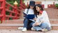 Two young pretty female teenagers starring idea while reading together on staircase in university Royalty Free Stock Photo