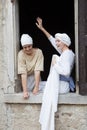 Pretty young actresses at the window in period costume, playing the role of common women attending the laundry