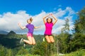 Two young pretty girls jumping on the grass in a mountain scener Royalty Free Stock Photo