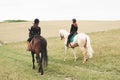 Two young pretty girls riding a horses on a field. They loves animals andhorseback riding Royalty Free Stock Photo