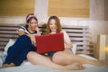 Two young pretty and happy Asian Chinese student girls together at home bedroom using internet social media in laptop computer Royalty Free Stock Photo