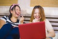 Two young pretty and happy Asian Chinese student girls together at home bedroom using internet social media in laptop computer Royalty Free Stock Photo