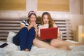 Two young pretty and happy Asian Chinese student girls together at home bedroom watching internet Korean drama with laptop