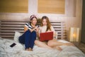 Two young pretty and happy Asian Chinese student girls together at home bedroom watching internet Korean drama with laptop