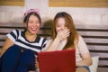 Two young pretty and happy Asian Korean student girls together at home bedroom using internet social media in laptop computer Royalty Free Stock Photo