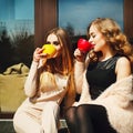 Two young pretty happy woman sitting outdoors and drinking coffee. Lifestyle concept of happy people. Royalty Free Stock Photo