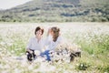 Two young pretty women having picnic with tea in chamomile field Royalty Free Stock Photo