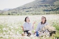 Two young pretty women having picnic with tea in chamomile field Royalty Free Stock Photo