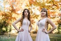 Two young princess wearing nice beige dress in autumn park. Fashion photo