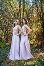 Two young princess wearing nice beige dress in autumn park. Fashion photo