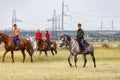 Two young riders go around their horses in the field before the races