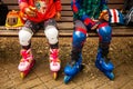 Two young rollers taking rest on bench in park after trainning, unrecognizible view without faces Royalty Free Stock Photo