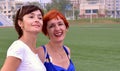 Two young russian sisters sincerely and naturally laughing with teeth in the summer evening on football field